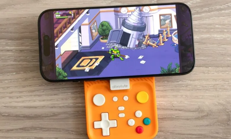 Phone with Teenage Mutant Ninja Turtles game attached to orange Abxylute controller.