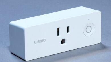 White WeMo smart plug with power outlet and button on gray surface.