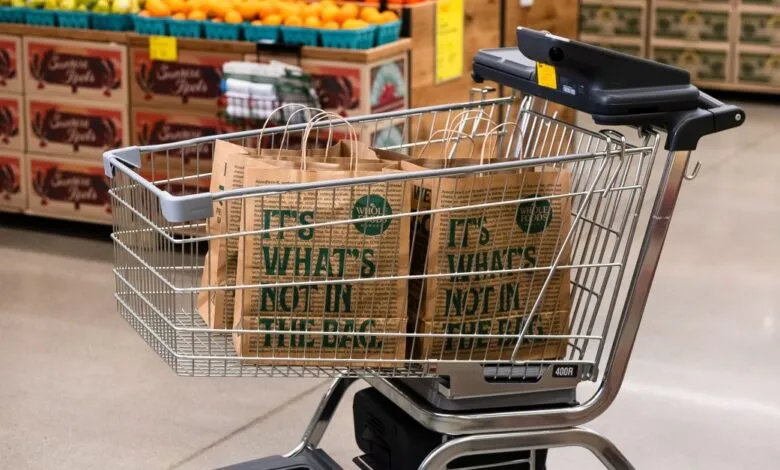 Shopping cart filled with Whole Foods paper bags.