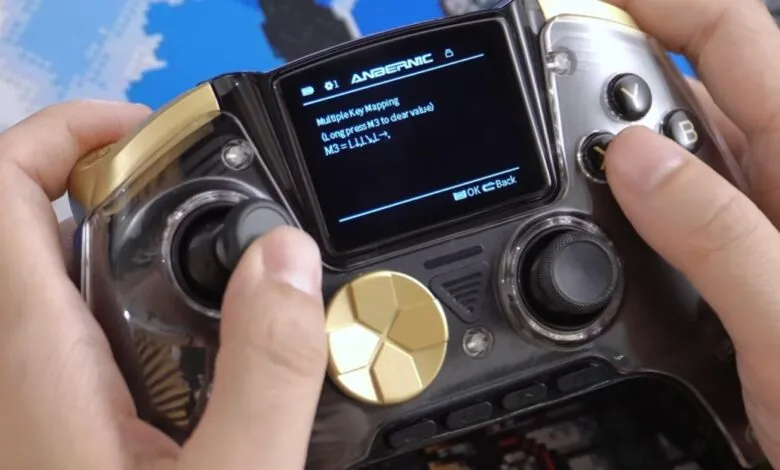Hands hold Anbernic controller showing key mapping options on screen.