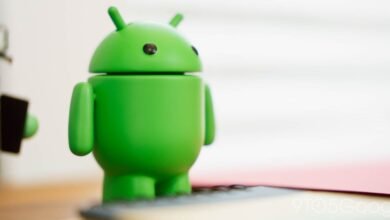 Close-up of a green Android robot figurine on a desk.