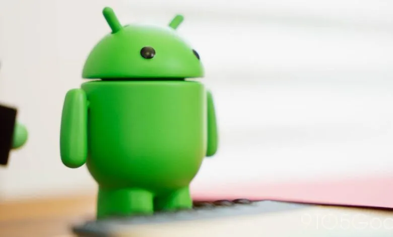 Close-up of a green Android robot figurine on a desk.