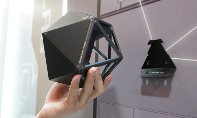 Hand holds a geometric ASUS ROG NeoCore Wi-Fi 8 router.