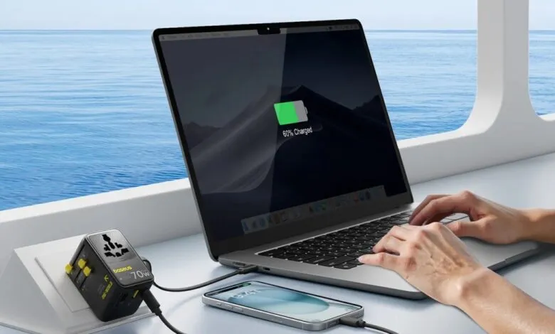 Laptop and phone charging with Baseus adapter by ocean view.