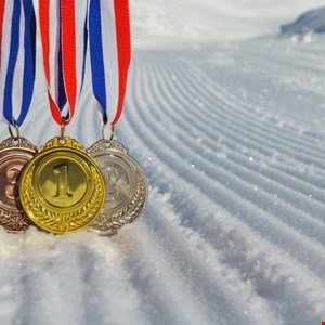 Gold, silver, and bronze medals with ribbons on a snowy surface.