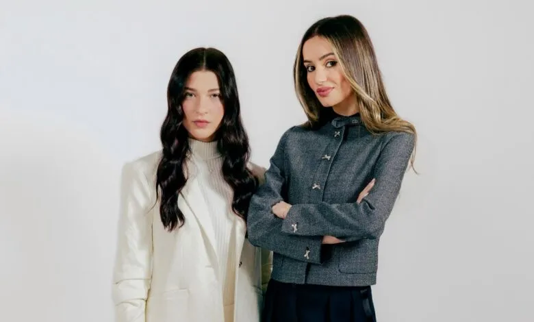 Two women pose in stylish blazers against a white backdrop.