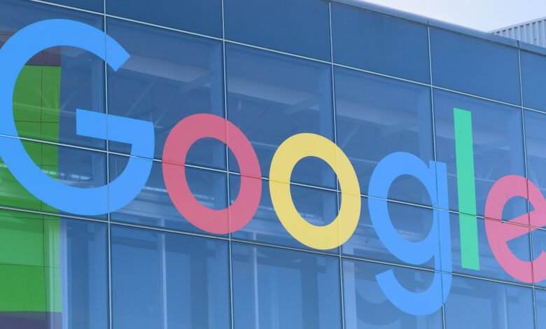 Google logo on the exterior of a glass building, reflecting the sky.