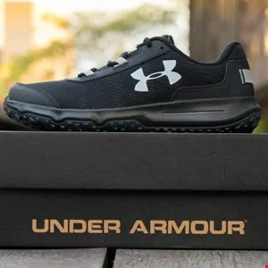 Black Under Armour athletic shoe sitting on top of its box.