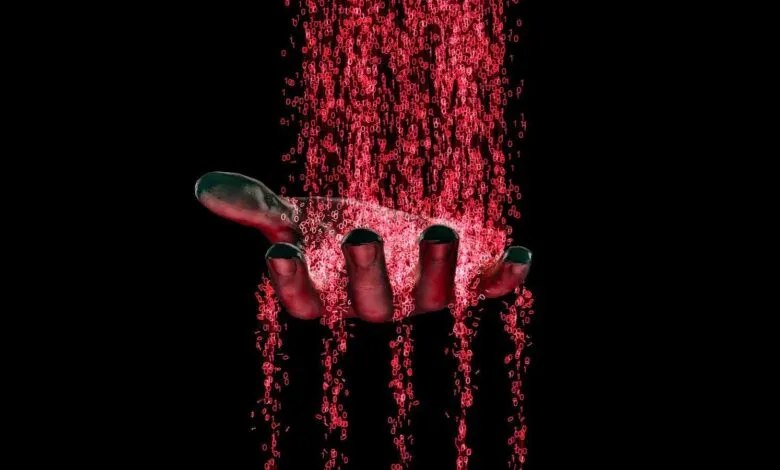 Hand catching falling red binary code against a black background.