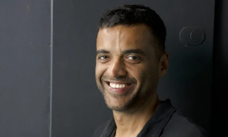 Portrait of Deepinder Goyal smiling against a dark gray background.