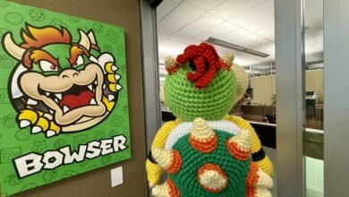 Crocheted Bowser doll next to Bowser poster in office setting.