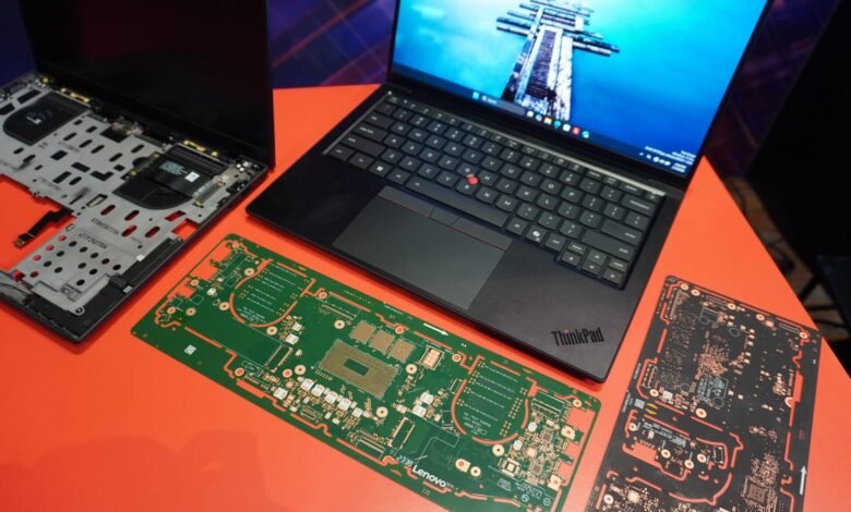 Disassembled ThinkPad laptop with circuit boards on orange surface.