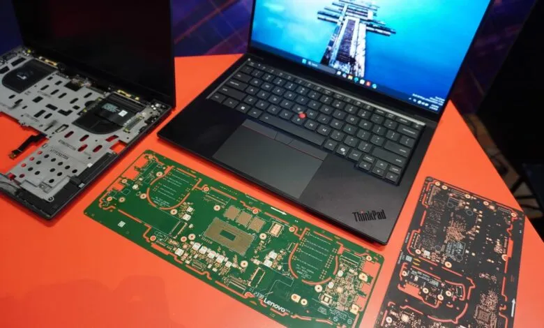 Disassembled ThinkPad laptop with circuit boards on orange surface.