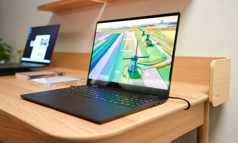 Laptop displays colorful tulip fields and windmills on a light wood desk.