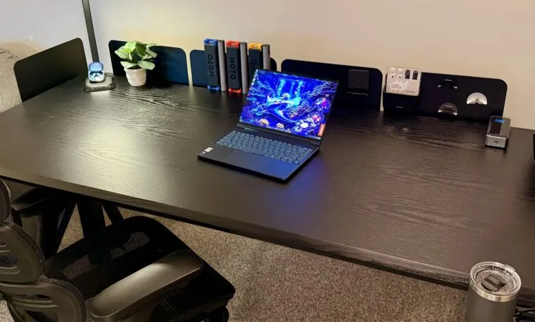 Dark wood desk with laptop, plant, and accessories, creating a modern workspace.