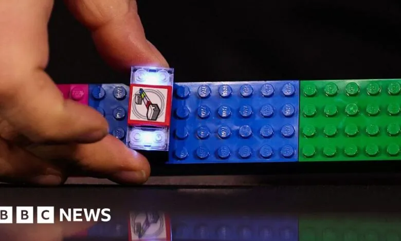 Hand places light-up LEGO brick on colorful LEGO strip.