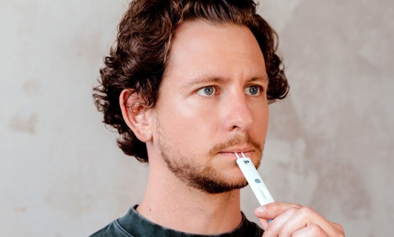 Man using oral swab test kit with thoughtful expression.
