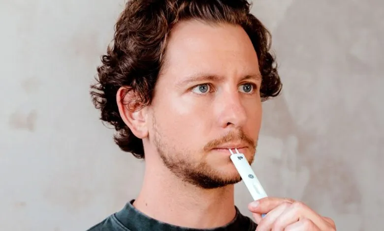 Man using oral swab test kit with thoughtful expression.