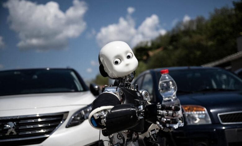 Humanoid robot holds water bottle outdoors, cars in background.
