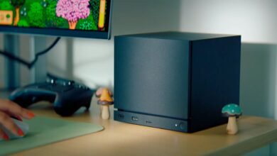 Compact black PC tower on desk with monitor and gaming controller.