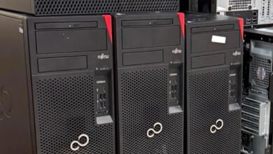 Three Fujitsu ESPRIMO computers lined up, black towers with red accents.