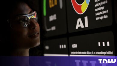 Woman wearing glasses looks at AI data on a screen.
