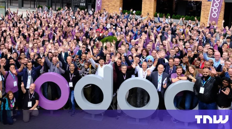 Large group of people waving in front of Odoo signage.