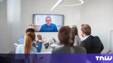 Team meeting with remote participant on large screen in modern office.