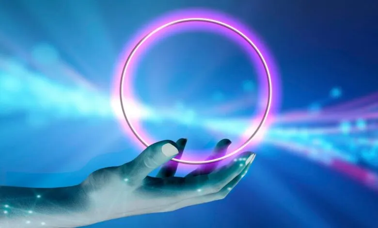 Hand holding a glowing pink circle against a blue digital background.