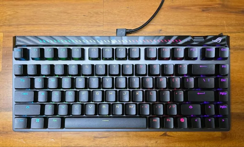 ROG Strix Scope NX TKL keyboard with RGB lighting on a wooden surface.