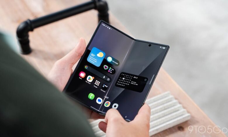 Person holding unfolded Samsung Galaxy Z Fold with widgets.