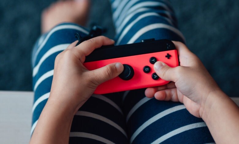 Child's hands hold a red Nintendo Switch Joy-Con controller.