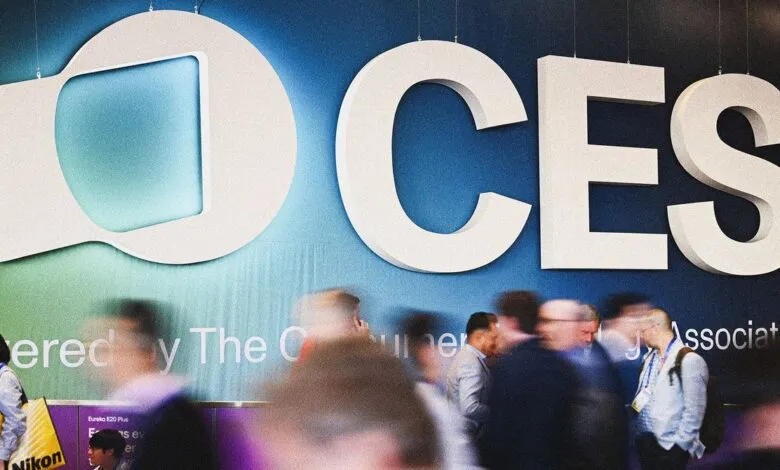 Blurred crowd walks past the large CES logo at a tech conference.