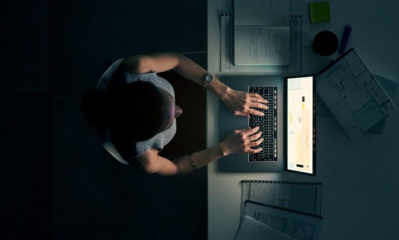 Overhead view of person typing on laptop in dimly lit workspace.