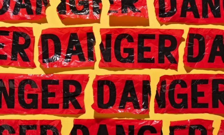 Red 'DANGER' tape pieces arranged on a bright yellow background.