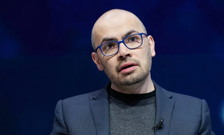 Close-up of a man with glasses speaking at an event.