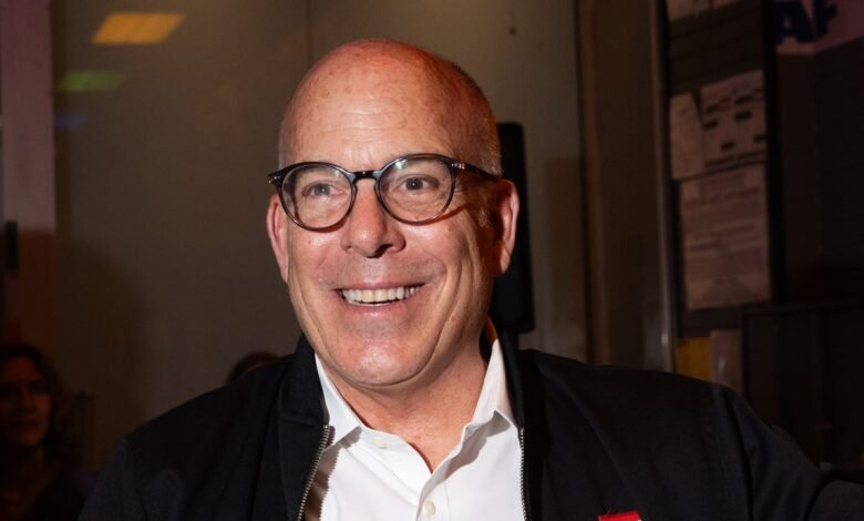 Jeffrey Katzenberg smiles wearing glasses and a black jacket.
