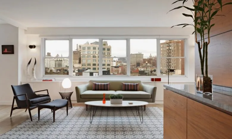 Bright living room with city view, sofa, chair, and patterned rug.