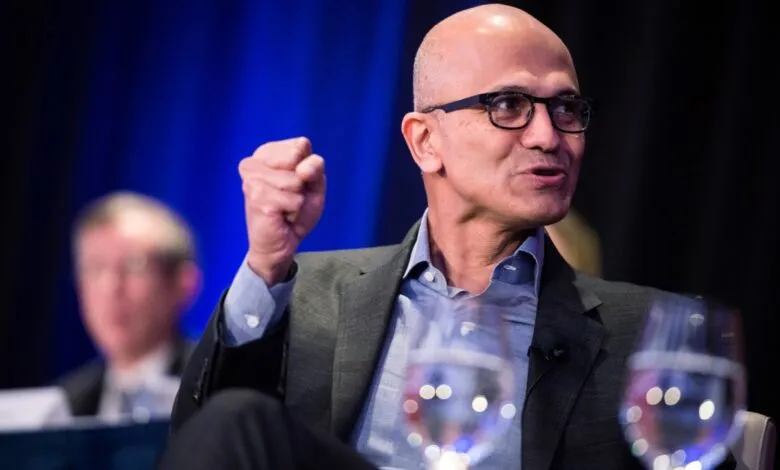Satya Nadella speaks with a raised fist at a conference.