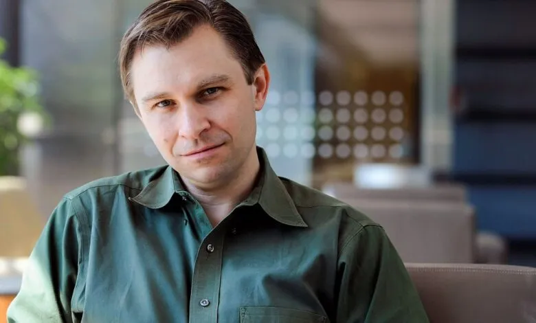 Portrait of a man with short hair wearing a green shirt.
