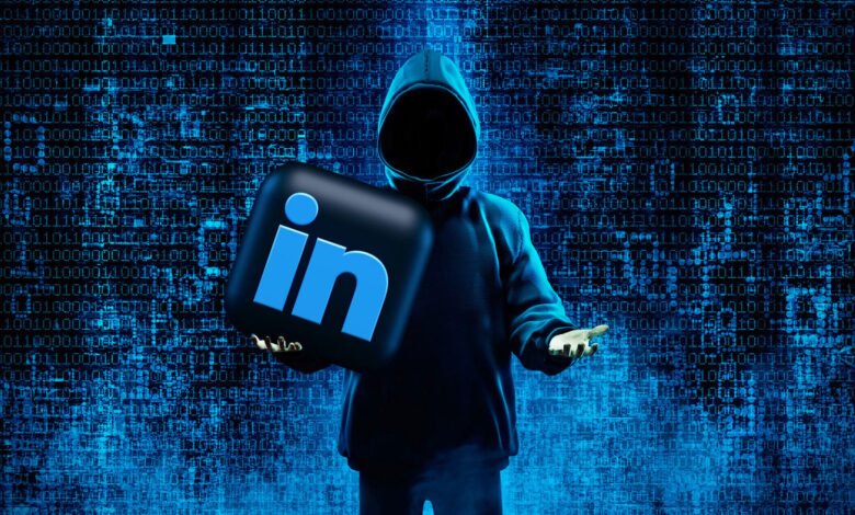 Hacker in hoodie holds LinkedIn logo against binary code background.