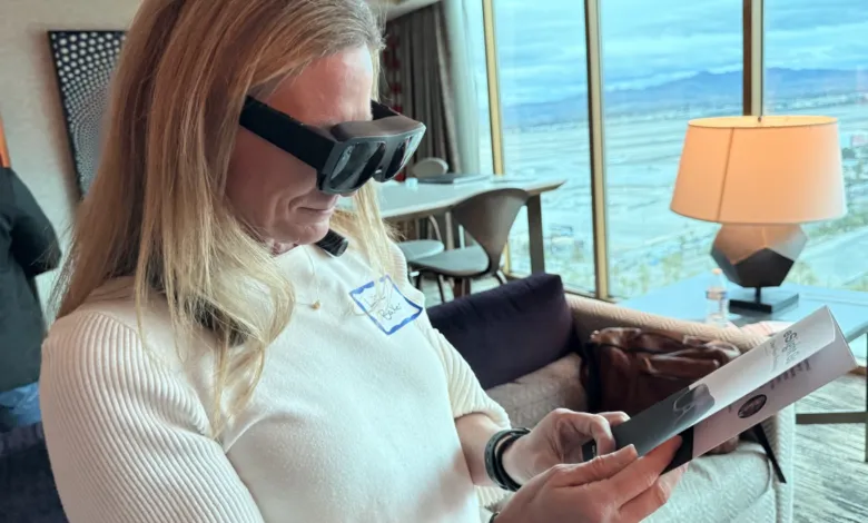 Woman wearing assistive eyewear reading brochure in bright room with city view.