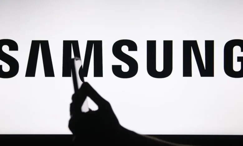 Samsung logo displayed with a hand holding a phone in silhouette.