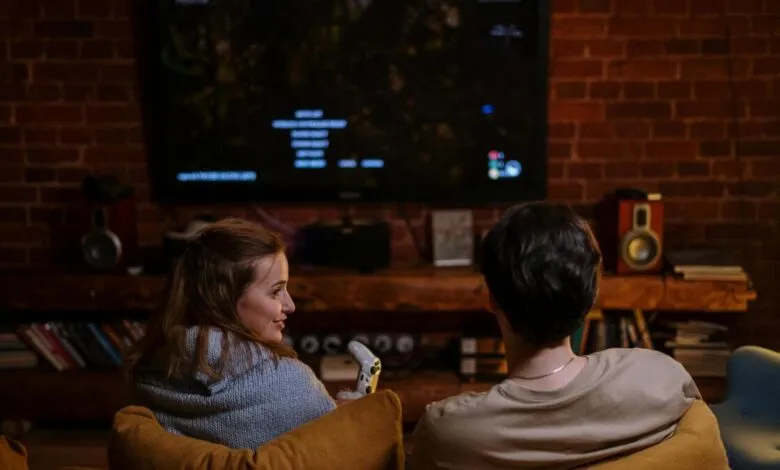 Couple relaxing on couch, playing video game on TV.
