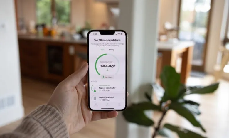 Person holds phone showing energy savings app with upgrade recommendations.