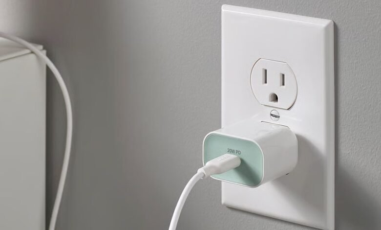White USB-C charger plugged into a wall outlet, cable attached.