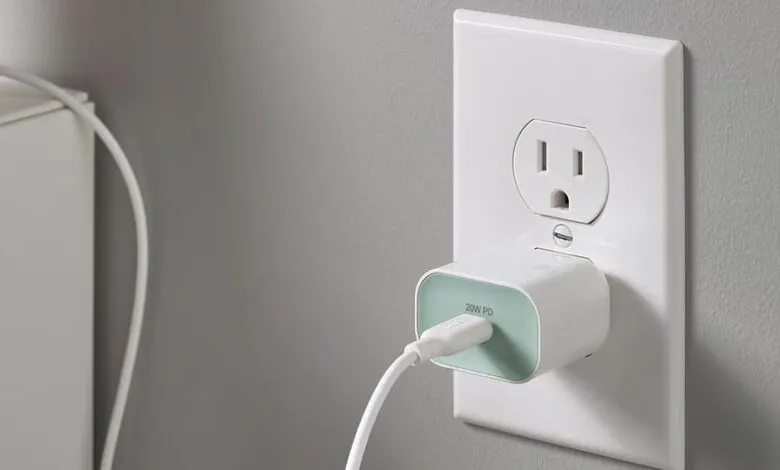 White USB-C charger plugged into a wall outlet, cable attached.