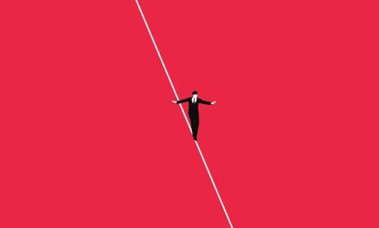 Businessman carefully walks on a tightrope against a red background.