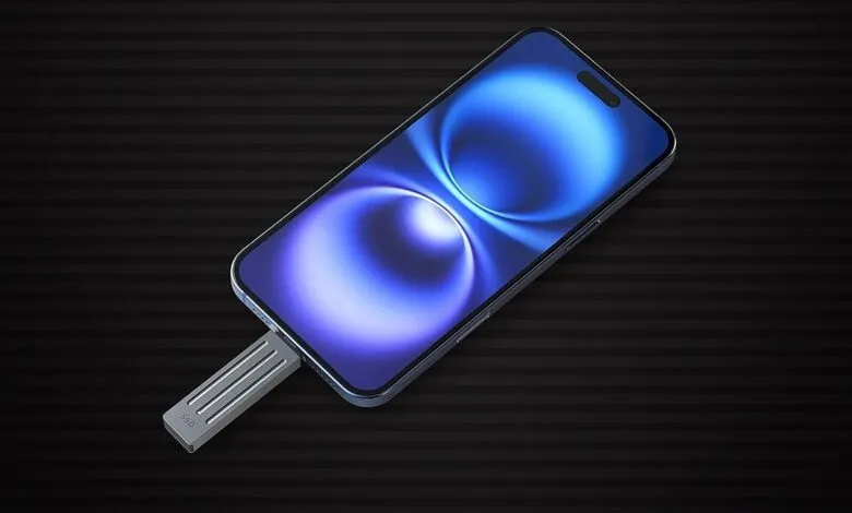 iPhone connected to a silver SSD drive on a striped background.