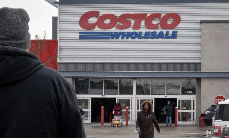 Costco store entrance with shoppers entering and exiting on a winter day.